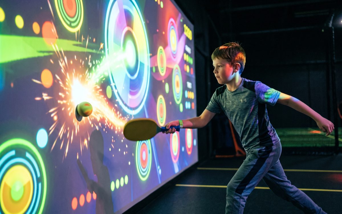Junge trifft mit dem Softschläger, der Ball explodiert in Licht